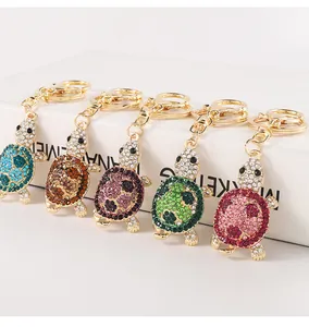 Detailed view of five colorful rhinestone turtle keychains on a white presentation stand