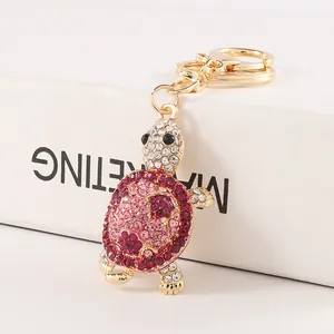 Elegant gold-tone keychain with sparkling pink rhinestone turtle on white block