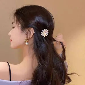 Gros plan d'une pince à cheveux fleurie et d'une boucle d'oreille perle