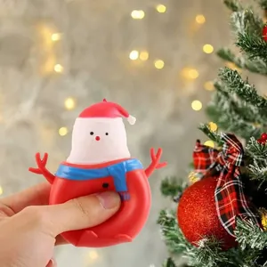 Hand die een kerstman sneeuwpop stress-speeltje knijpt in een warme kerstomgeving