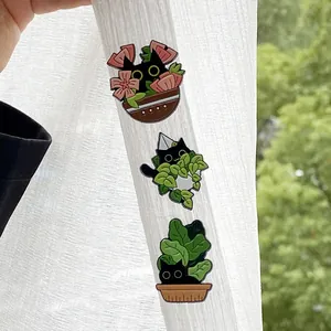 Detailed view of three cute black cat enamel pins featuring floral and plant themes.