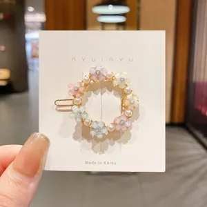 Vue détaillée d'une épingle à cheveux fleurie avec fleurs pastel et perles sur carte.