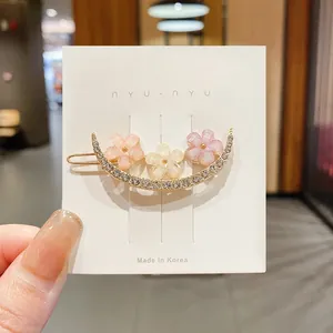 Détail d'une pince à cheveux fleurie avec des strass étincelants sur carte.