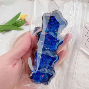 Detailansicht eines blauen, glitzernden Stern-Quetschtier-Spielzeugs in Klarsichtverpackung