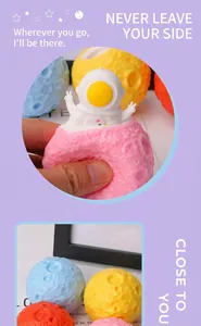 Detailed view of hand squeezing pink planet squishy toy with a white astronaut popping out