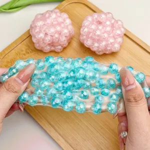 Close-up of stretchy transparent stress relief toy filled with sparkling blue pearls.
