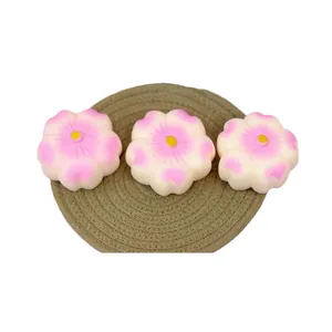 Set mit drei rosa Kirschblüten-Squishy-Spielzeugen zum Stressabbau auf einer gewebten Matte