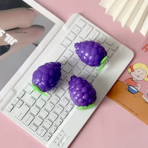 Detailed view of three purple grape slow-rebound squeeze toys on a white desk setup