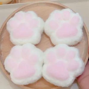 Gros plan de quatre jouets anti-stress en peluche patte de chat blanc et rose sur bois