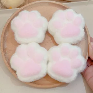 Gros plan de quatre jouets anti-stress en peluche en forme de patte de chat sur un plateau.