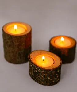 Macro view of three rustic natural wood log candle holders with glowing warm tea lights