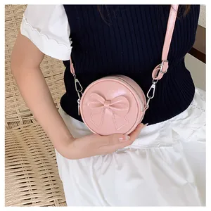 Macro detail of a cute pink round girl's crossbody bag featuring a stylish bow decoration