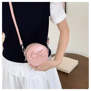 Detail view of a sweet pink mini round crossbody bag with a decorative bow for girls