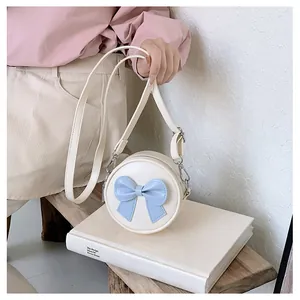 Sweet cream round shoulder bag for girls with a decorative light blue bow detail