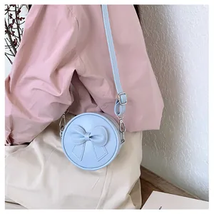 Detailed shot of a sweet light blue mini round crossbody bag with a decorative bow