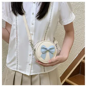 Detail view of a cute mini round crossbody bag for girls with a blue bow decoration