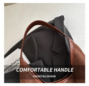 Dettaglio di borsa tote retrò in pelle scamosciata marrone con sfondo blazer