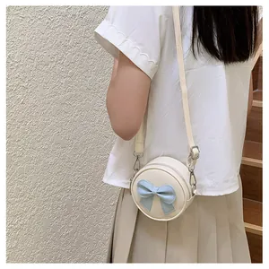 Sweet cream round crossbody bag for girls featuring a blue bow accent on pleated skirt