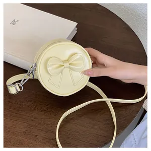 Close-up of a cute yellow mini round crossbody bag with a stylish bow detail for girls