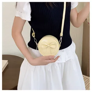 Close-up of a sweet yellow mini round bag with bow detail, worn as a crossbody bag