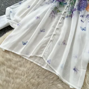 Detailed view of white chiffon blouse featuring purple floral prints and round buttons