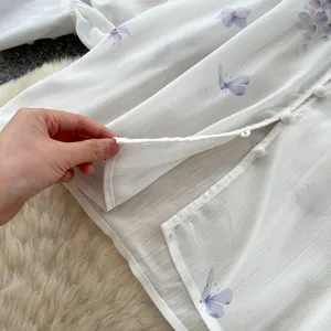 Close-up of white chiffon blouse with purple butterfly print and fine button detail