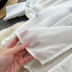 Detail of sheer white floral blouse with elegant lantern sleeves and textured fabric.