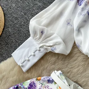 Close-up of elegant lantern sleeve cuff with covered buttons and floral printed shorts detail