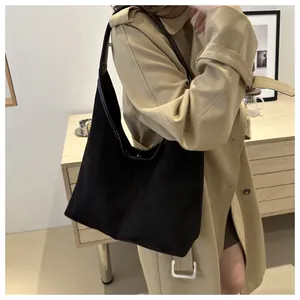 Grande borsa tote nera indossata con un trench beige per un look da ufficio chic.