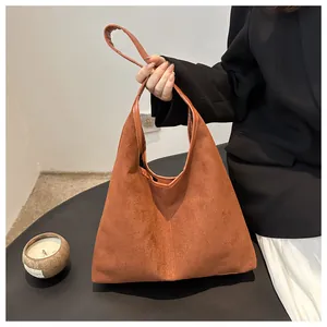 Dettaglio di una borsa tote in pelle scamosciata marrone con tracolla minimalista