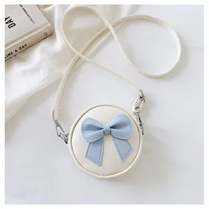 Detailed view of a sweet white mini round crossbody bag with a blue bow for girls