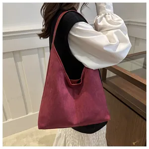 Primo piano di una grande borsa tote in pelle scamosciata bordeaux indossata a spalla