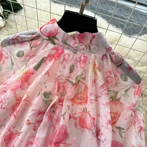 Close-up of pink floral print blouse with elegant stand collar and lantern sleeves.