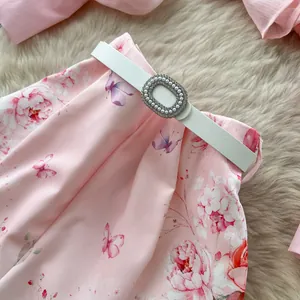 Close-up of pink floral high-waisted shorts featuring a white belt with pearl buckle