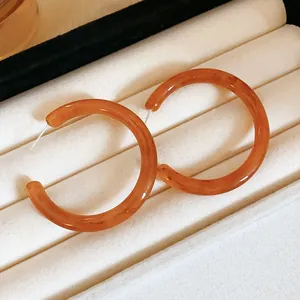 Exquisite amber resin hoop earrings in a jewelry box, elegant Maillard style accessories.