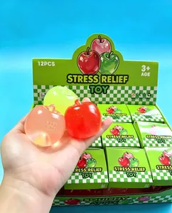 Mano sosteniendo juguetes squishy de manzana traslúcidos con caja de exhibición