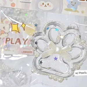 Detailansicht eines transparenten Katzenpfoten-Squishys mit Perlen und Schleife.