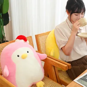 Cute pink penguin plush toy wearing a Santa hat placed on a cozy wooden chair for home decor