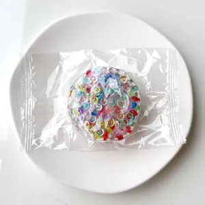 Close-up of a colorful bead-filled stress relief squishy toy ball in clear plastic packaging