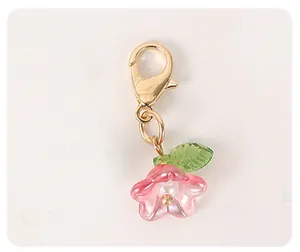 Detail showing a pink resin flower charm with a green leaf and golden lobster clasp hook
