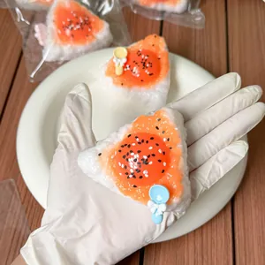 Close-up of a triangle rice ball squeeze toy with orange filling and small spoon detail