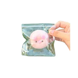 Cute pink pig-shaped squishy stress relief toy in transparent packaging held by hand