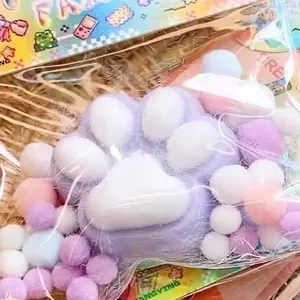 Weiches Lavendel-Katzenpfoten-Squishy-Spielzeug mit bunten Pompons in einer Geschenktüte