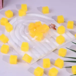Detailed macro view of yellow mango cube stress relief squishy toys on a white display tray
