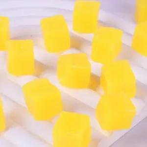 Macro view of bright yellow cube-shaped mango squishy toys on a white display tray