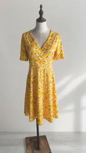 Detailansicht des lebhaften gelben Blumendrucks und des eleganten V-Ausschnitts am Kleid.