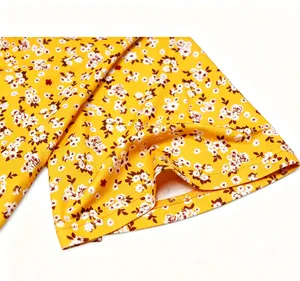 Nahaufnahme des gelben Blumenmusters und der Saumnaht an einem schicken V-Ausschnitt Kleid