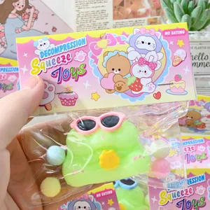 Close-up of a cute green frog squeeze toy in its colorful transparent packaging