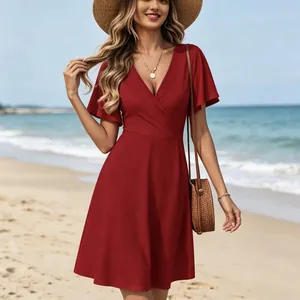 Rotes Kleid mit V-Ausschnitt und Flatterärmeln in einer schönen Strandkulisse.