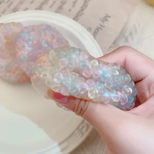 Close-up detail of a colorful bead squishy stress relief toy being squeezed by hand.